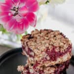 A plate of mixed berry bars on a table with flowers.
