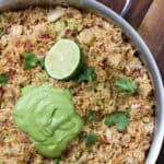 One-pan arroz con pollo topped with vibrant avocado cilantro lime crema, garnished with fresh cilantro and lime. A flavorful, dairy-free and gluten-free chicken and rice dinner perfect for meal prep or casual hosting