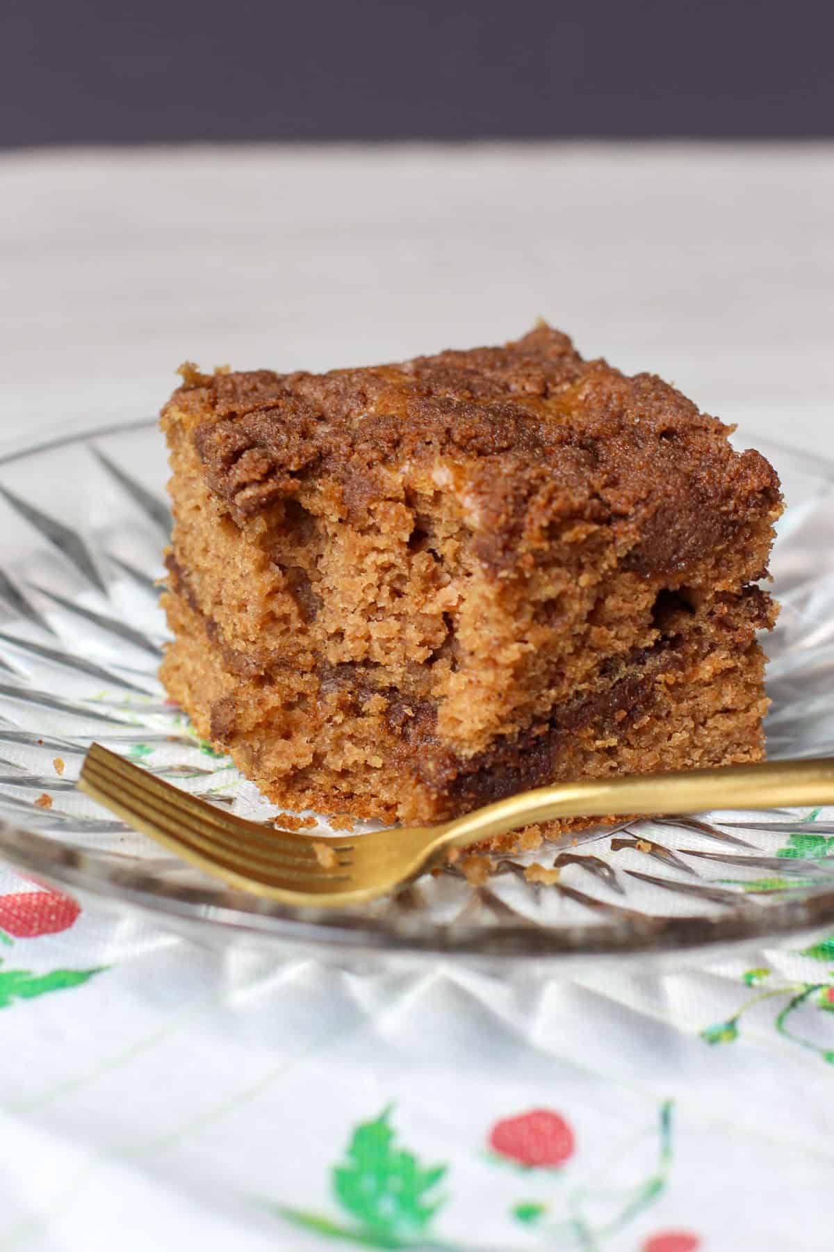 A golden slice of gluten-free cinnamon streusel coffee cake on a plate, topped with crumbly coconut sugar streusel and served with a cup of coffee. Ideal for brunch or a cozy weekend bake.