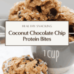 Close-up of coconut chocolate chip protein bites stacked in a 1-cup measuring cup, topped with shredded coconut and chocolate chips, on a white tray.