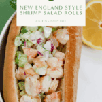Overhead image of a New England shrimp salad roll served in a gluten-free hot dog bun with chopped celery, onion, and creamy avocado mayo. Garnished with parsley and served with lemon wedge.