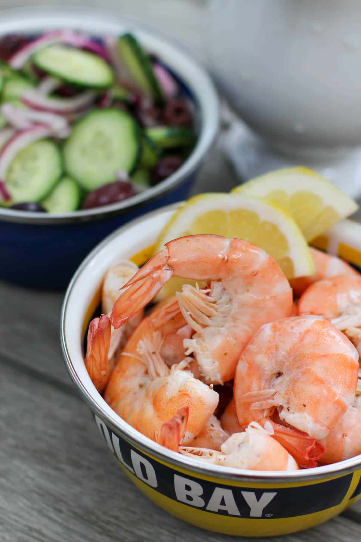 A bowl of peel & eat shrimp seasoned with Old Bay and served with lemon wedges. The shrimp are plump, pink, and perfectly cooked.