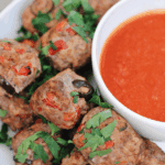Plate of pizza burger bites with marinara dipping sauce, garnished with fresh parsley.