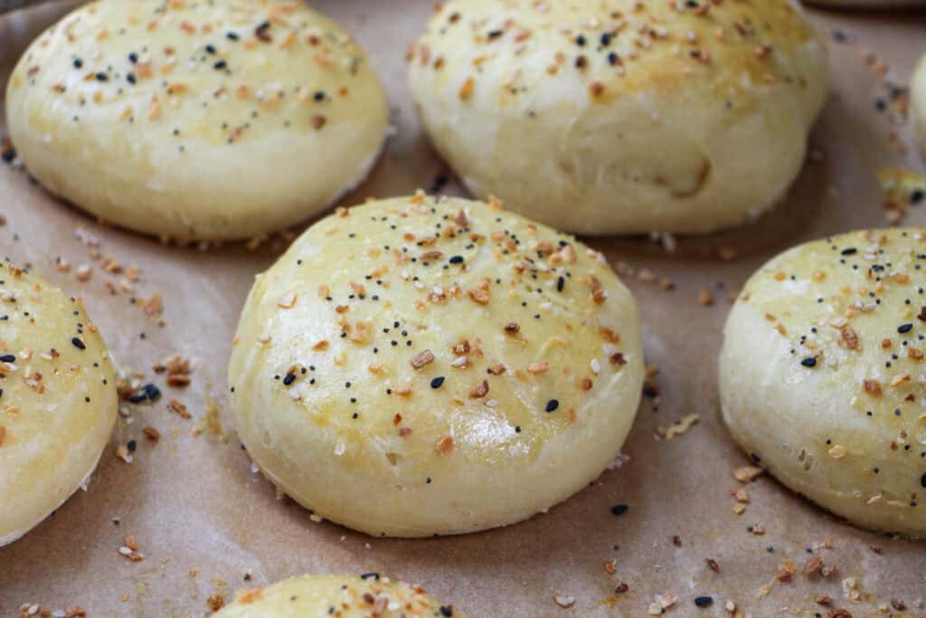 Homemade fluffy everything but the bagel burger buns fresh out of the oven on a baking sheet.