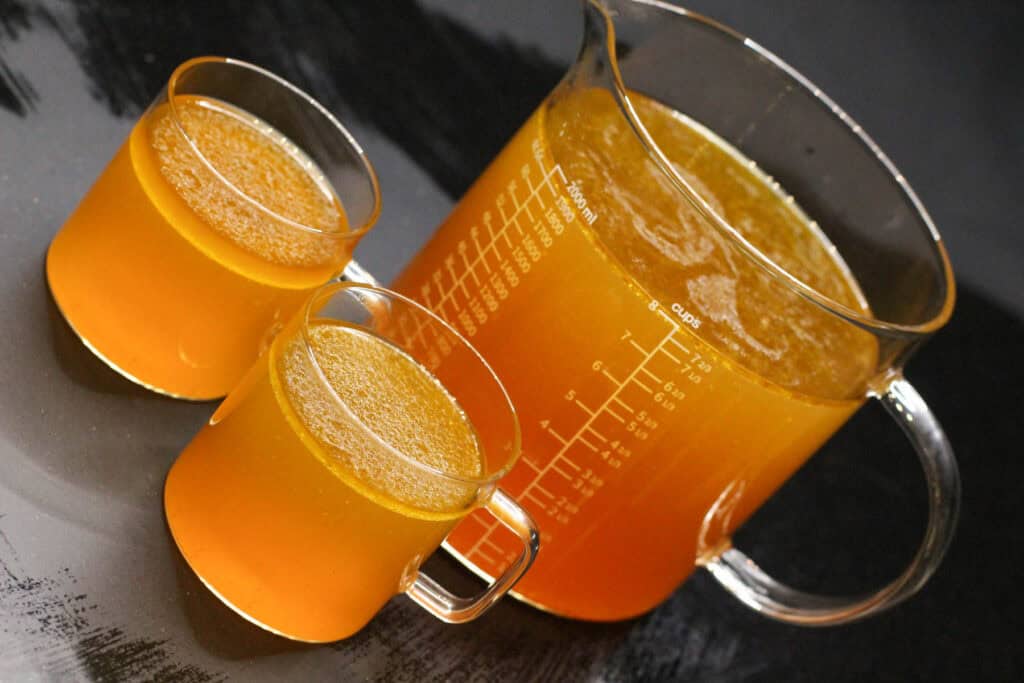 Bright orange juice in measuring glass and cups, healthy beverage for fitness and entertainment.