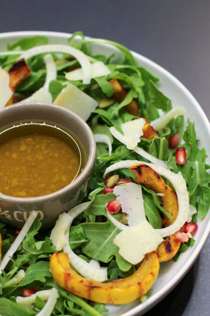 A fall salad featuring roasted delicata squash rings, shaved fennel, arugula, pomegranate seeds, and toasted pumpkin seeds drizzled with a citrus vinaigrette.