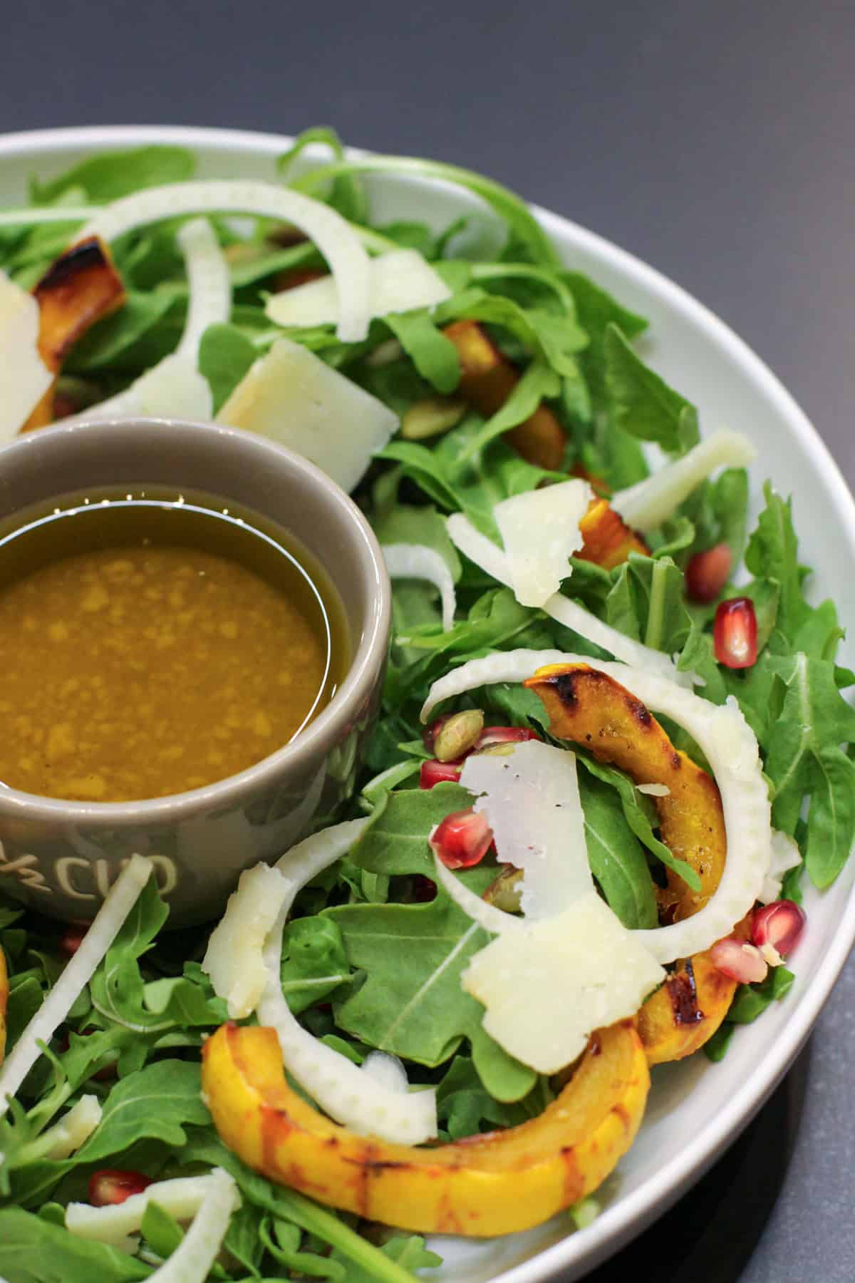 A fall salad featuring roasted delicata squash rings, shaved fennel, arugula, pomegranate seeds, and toasted pumpkin seeds drizzled with a citrus vinaigrette.