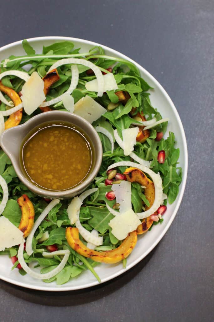 A fall salad featuring roasted delicata squash rings, shaved fennel, arugula, pomegranate seeds, and toasted pumpkin seeds drizzled with a citrus vinaigrette.
