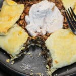 A golden-brown salted maple pecan galette with glossy caramelized filling and flaky folded crust, served with cinnamon whipped cream.