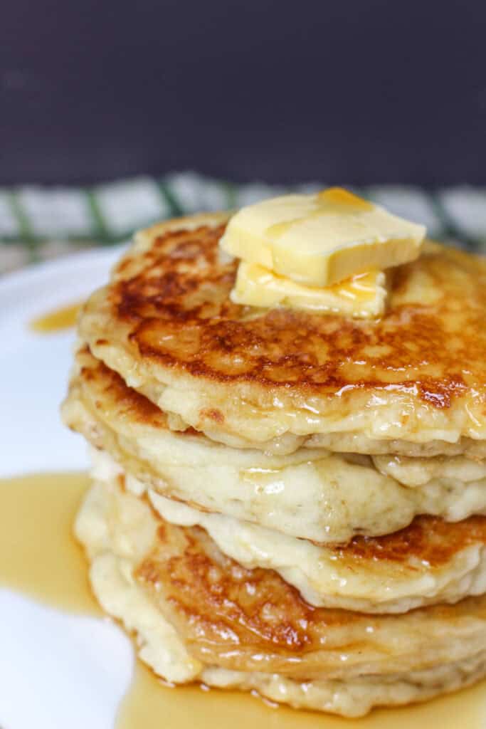 Stack of golden gluten-free buttermilk pancakes topped with butter and syrup