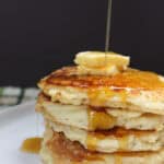 Stack of golden gluten-free buttermilk pancakes topped with butter and syrup