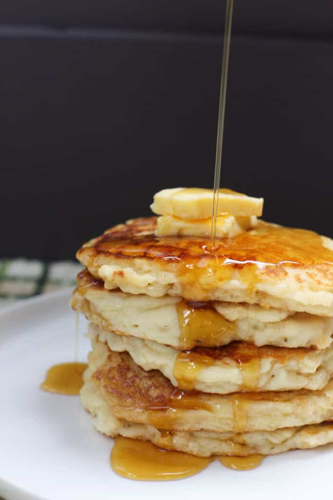 Stack of golden gluten-free buttermilk pancakes topped with butter and syrup