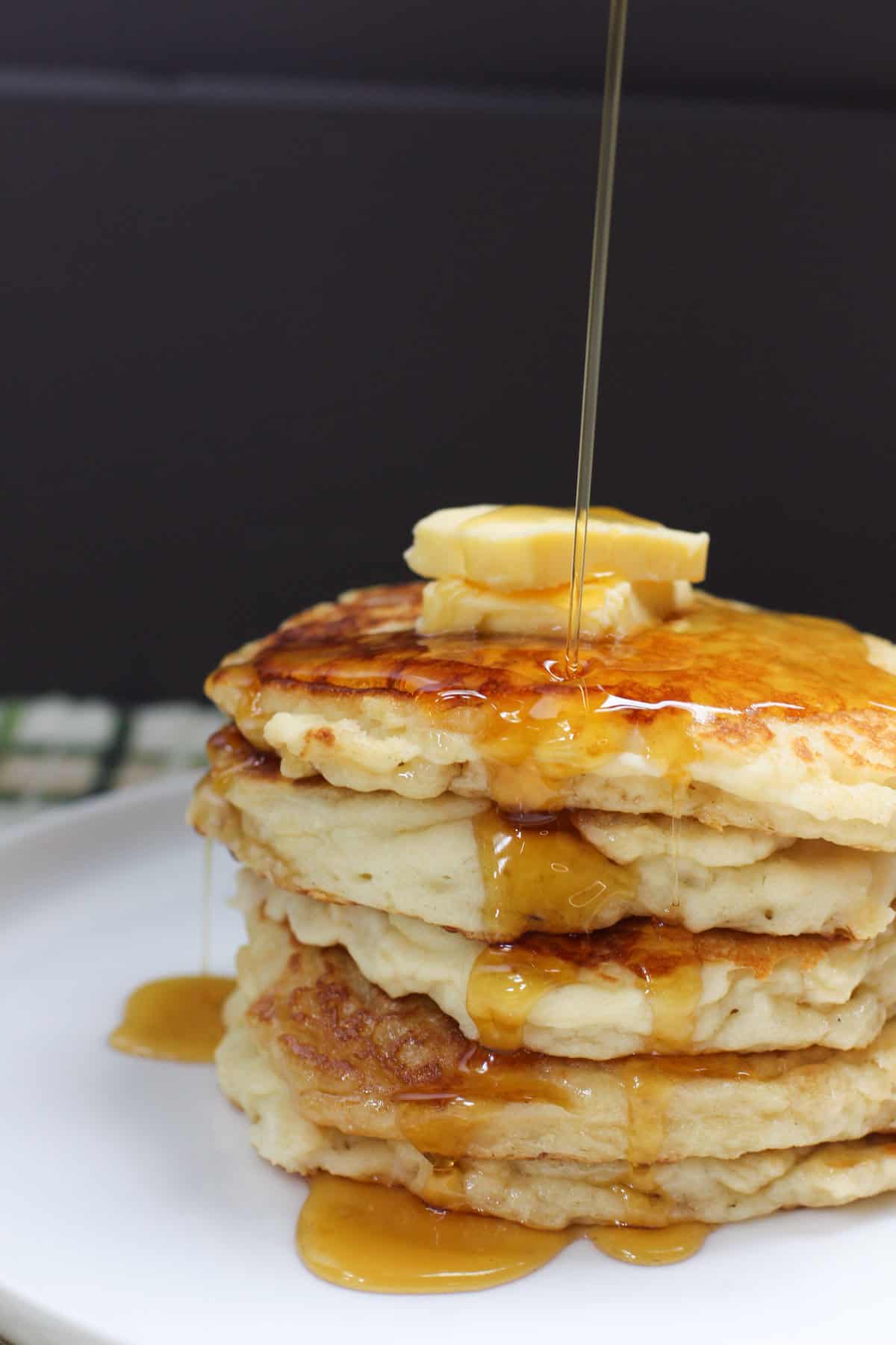 Stack of golden gluten-free buttermilk pancakes topped with butter and syrup