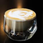 Brown sugar latte made at home with espresso and frothed milk in a glass cup on a dark background