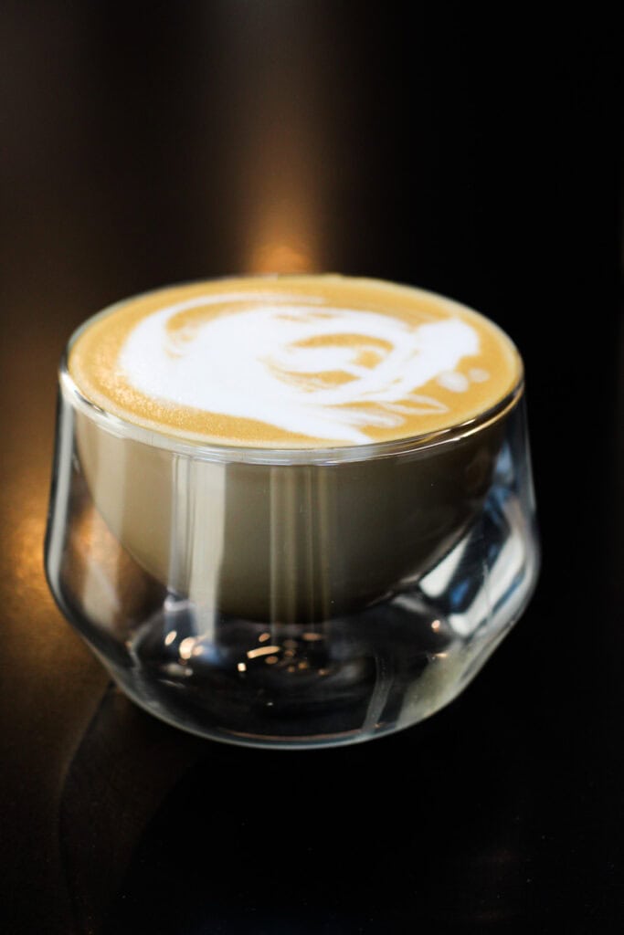 Brown sugar latte made at home with espresso and frothed milk in a glass cup on a dark background