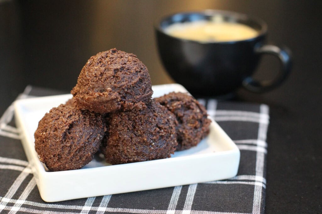 Brownie batter protein bites stacked in a glass bowl, made with cocoa powder, almond flour, and chocolate protein powder.