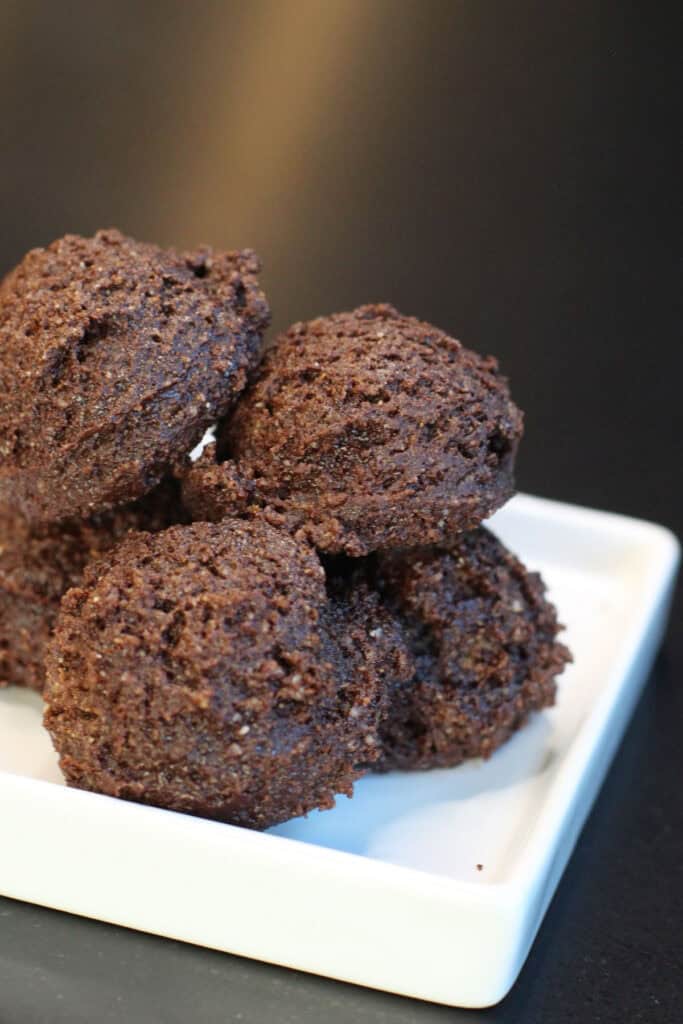 Brownie batter protein bites stacked in a glass bowl, made with cocoa powder, almond flour, and chocolate protein powder.
