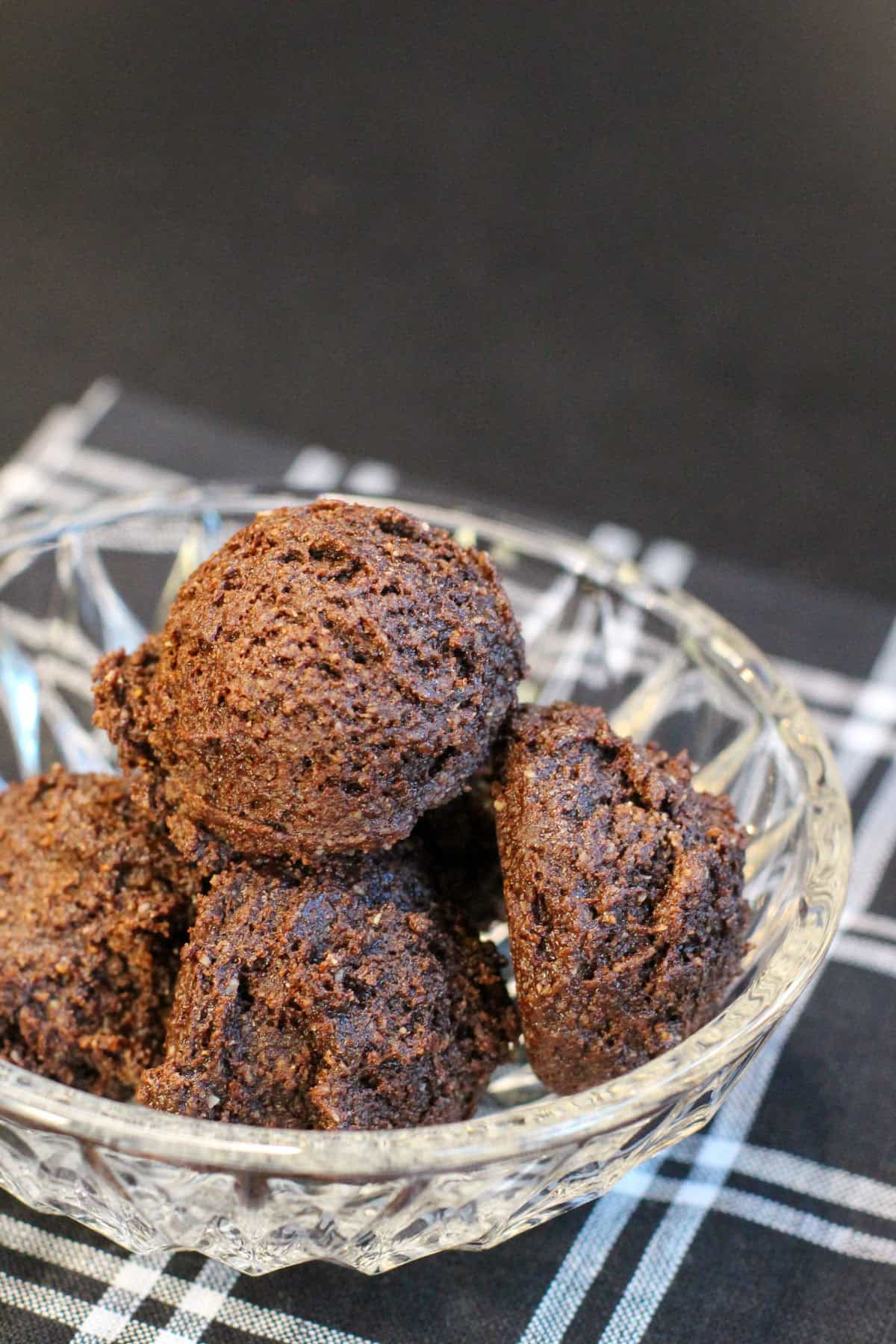 Brownie batter protein bites stacked in a glass bowl, made with cocoa powder, almond flour, and chocolate protein powder.