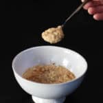 Creamy stovetop protein oatmeal with maple syrup in a white bowl on a dark background