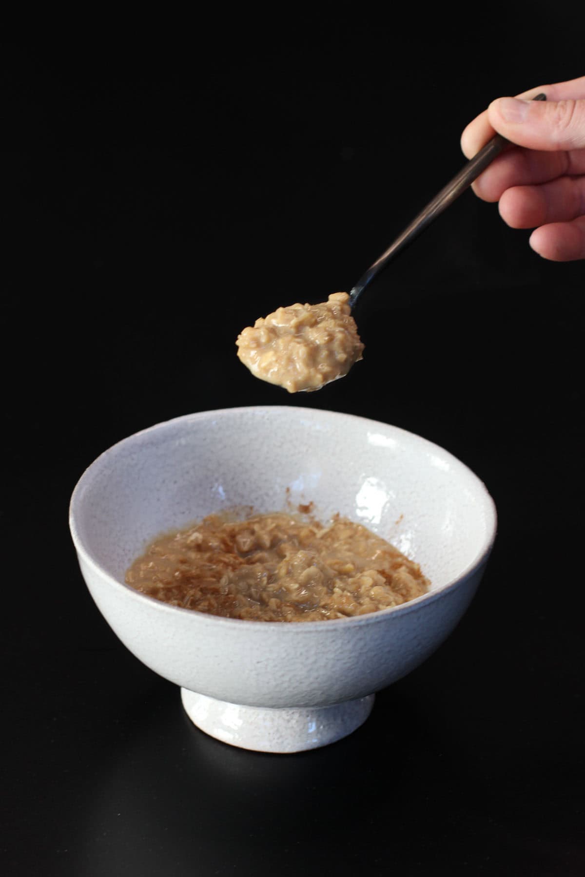 Creamy stovetop protein oatmeal with maple syrup in a white bowl on a dark background