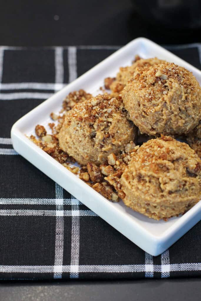 No-bake maple pecan protein bites made with almond flour, chopped pecans, maple syrup, and cinnamon, arranged on a white serving dish.