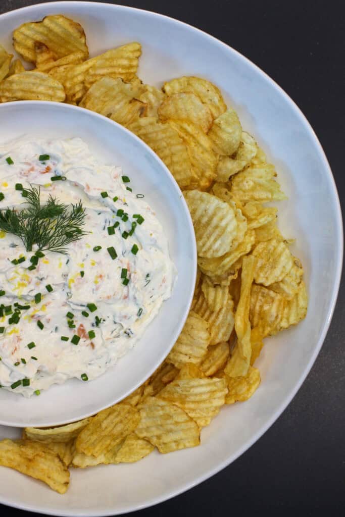 Creamy smoked salmon dip garnished with fresh dill and chives, served with kettle chips for easy entertaining