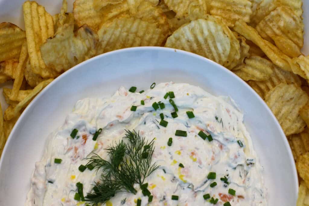 Creamy smoked salmon dip garnished with fresh dill and chives, served with kettle chips for easy entertaining