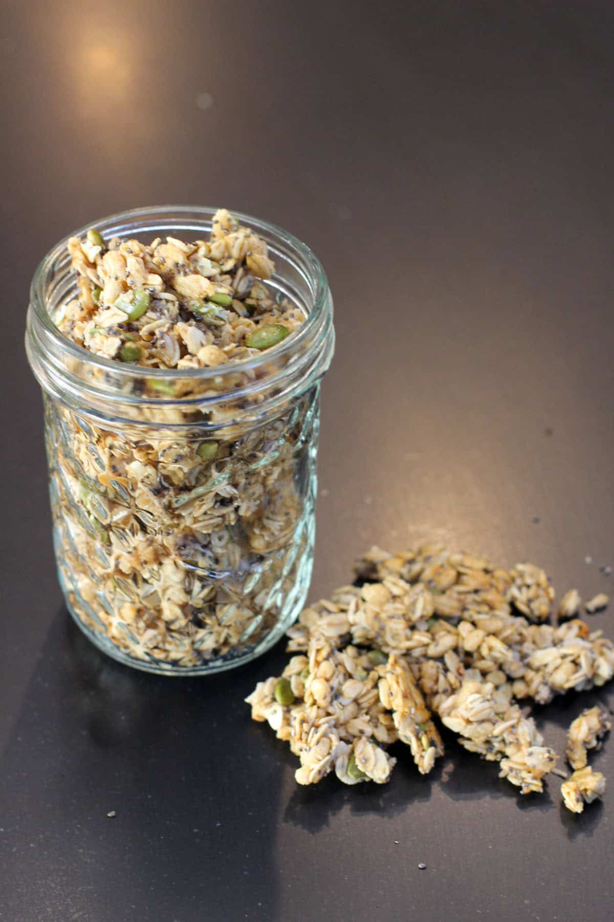 Crunchy ancient grain granola with oats, chia seeds, pumpkin seeds, and shredded coconut in a glass jar