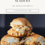 Baked buffalo chicken sliders on Hawaiian rolls with melted cheese and garlic butter tops stacked on black plate.