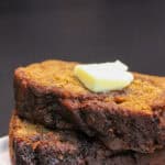 Brown butter cinnamon swirl banana bread slices stacked on a white plate, topped with melting butter, showing a moist crumb and rich, caramelized edges