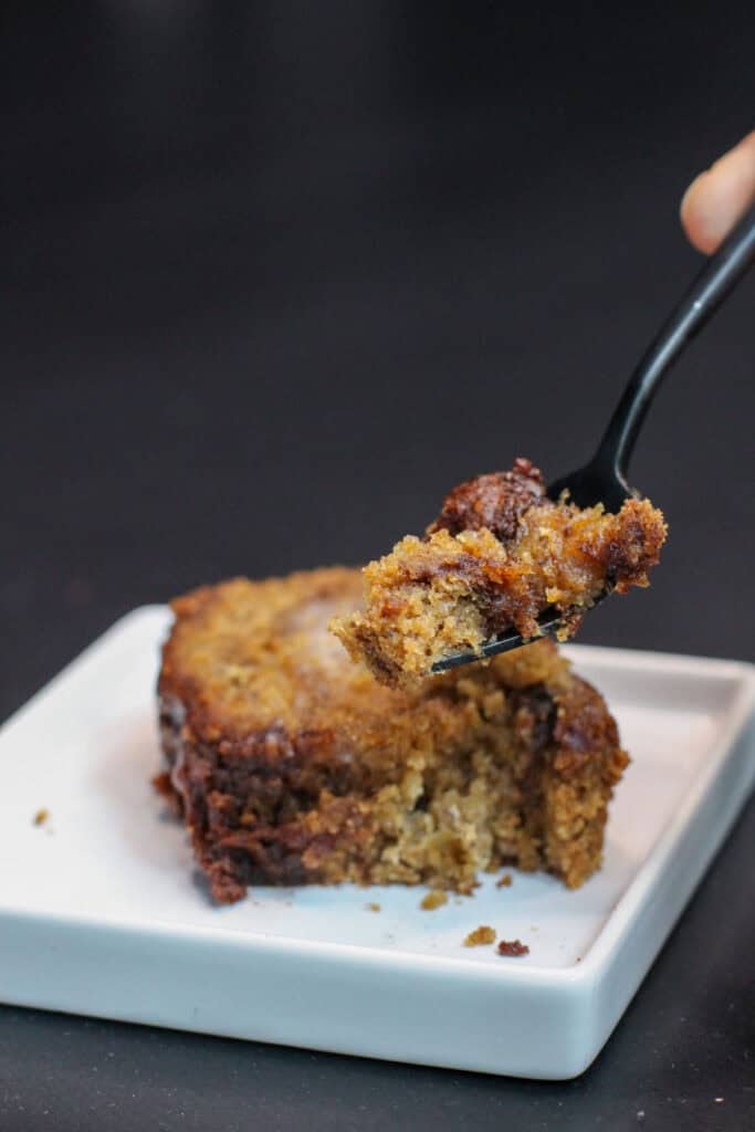 Brown butter cinnamon swirl banana bread slices stacked on a white plate, topped with melting butter, showing a moist crumb and rich, caramelized edges