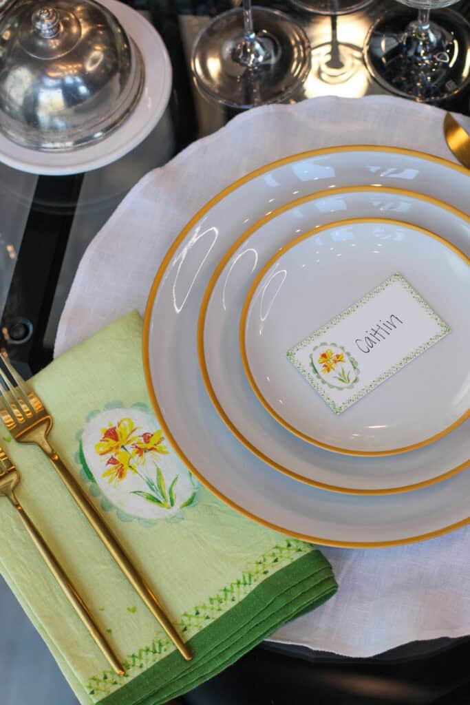 Minimal spring tablescape with white plates, gold rim detail, linen napkin, and handwritten place card