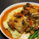 French countryside chicken with creamy mashed potatoes, sautéed mushrooms, carrots, crispy pancetta, and green beans with toasted almonds in a light pan sauce.