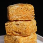Sweet potato buttermilk biscuits stacked in a close-up, showing flaky, golden layers and soft interior texture