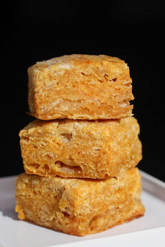Sweet potato buttermilk biscuits stacked in a close-up, showing flaky, golden layers and soft interior texture