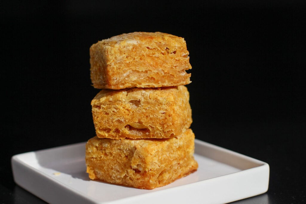 Sweet potato buttermilk biscuits stacked in a close-up, showing flaky, golden layers and soft interior texture