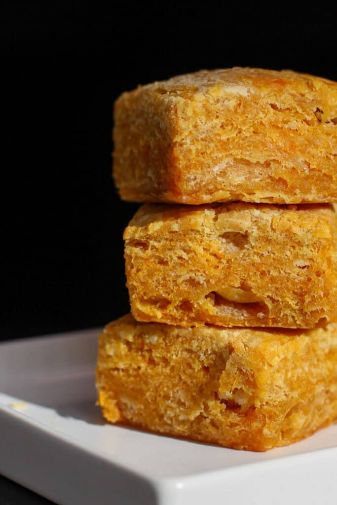 Sweet potato buttermilk biscuits stacked in a close-up, showing flaky, golden layers and soft interior texture
