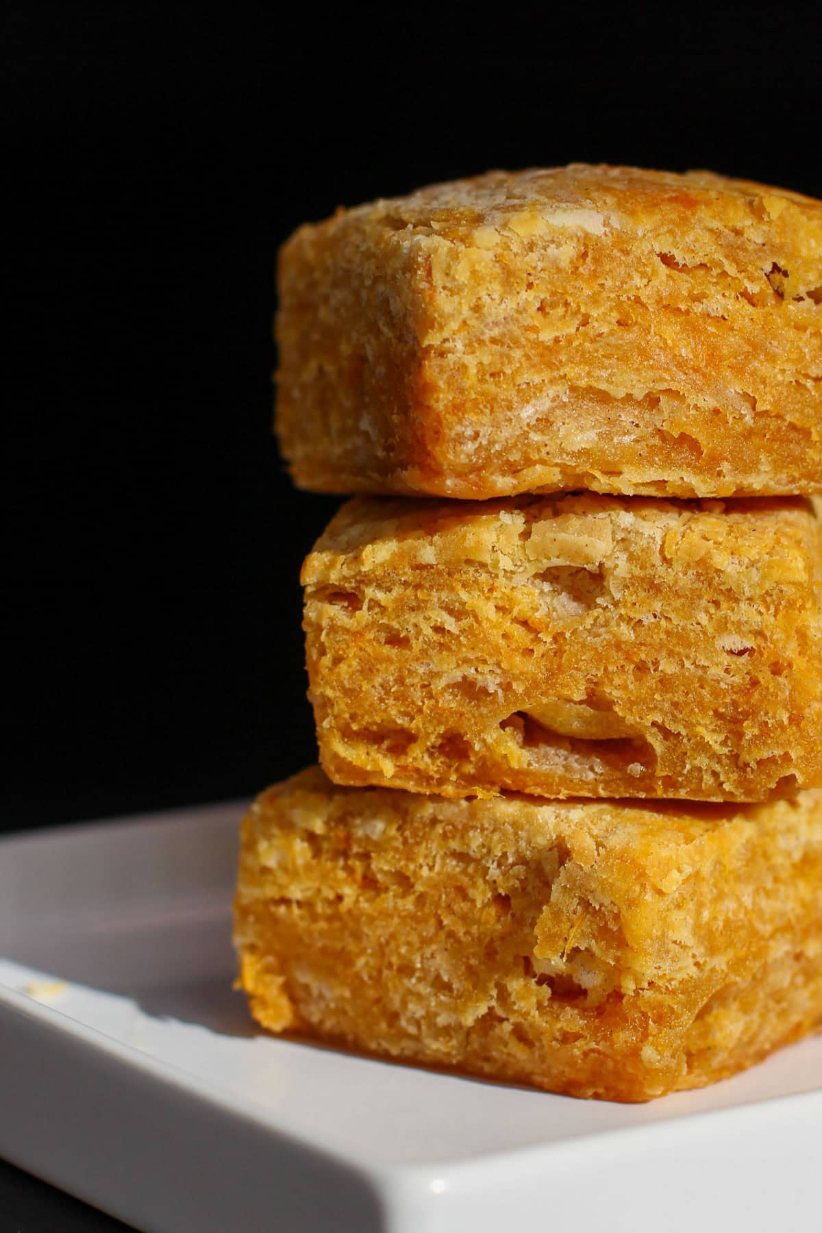 Sweet potato buttermilk biscuits stacked in a close-up, showing flaky, golden layers and soft interior texture