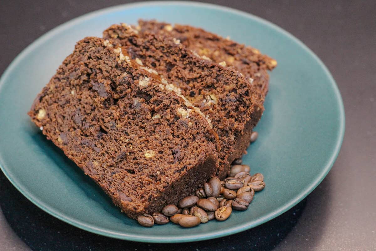 Three slices of brown butter mocha banana bread made with espresso powder and dark chocolate chunks, served with coffee beans for a cozy coffeehouse-inspired breakfast or snack.