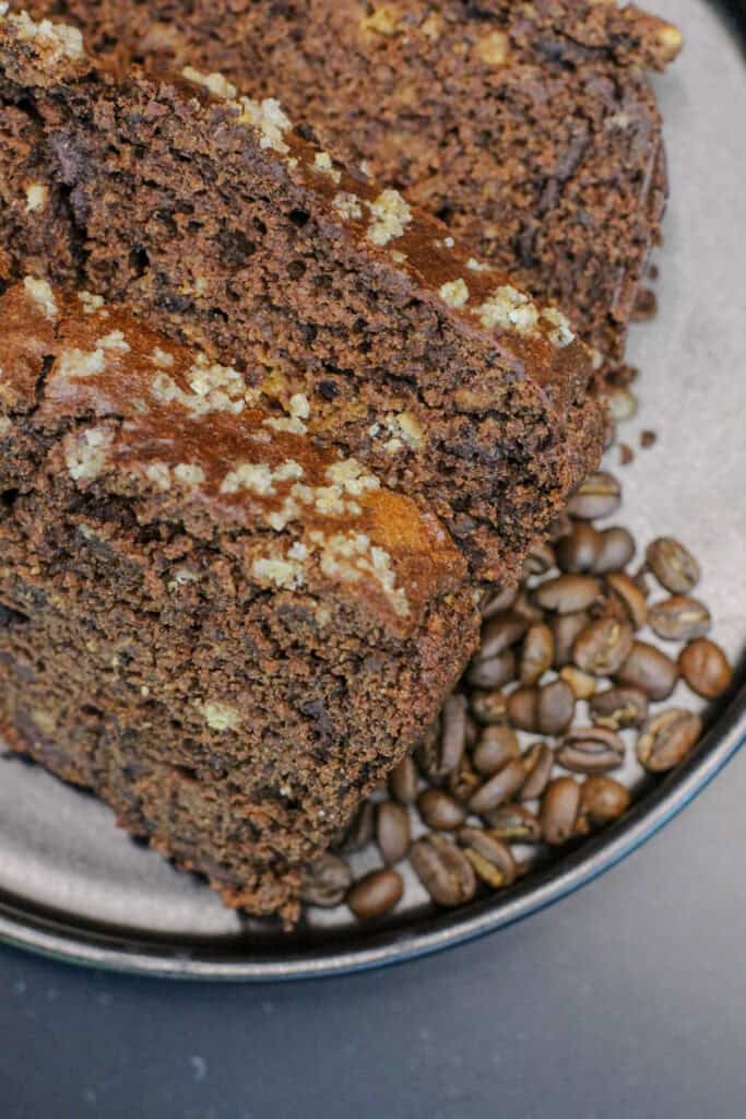 Three slices of brown butter mocha banana bread made with espresso powder and dark chocolate chunks, served with coffee beans for a cozy coffeehouse-inspired breakfast or snack.