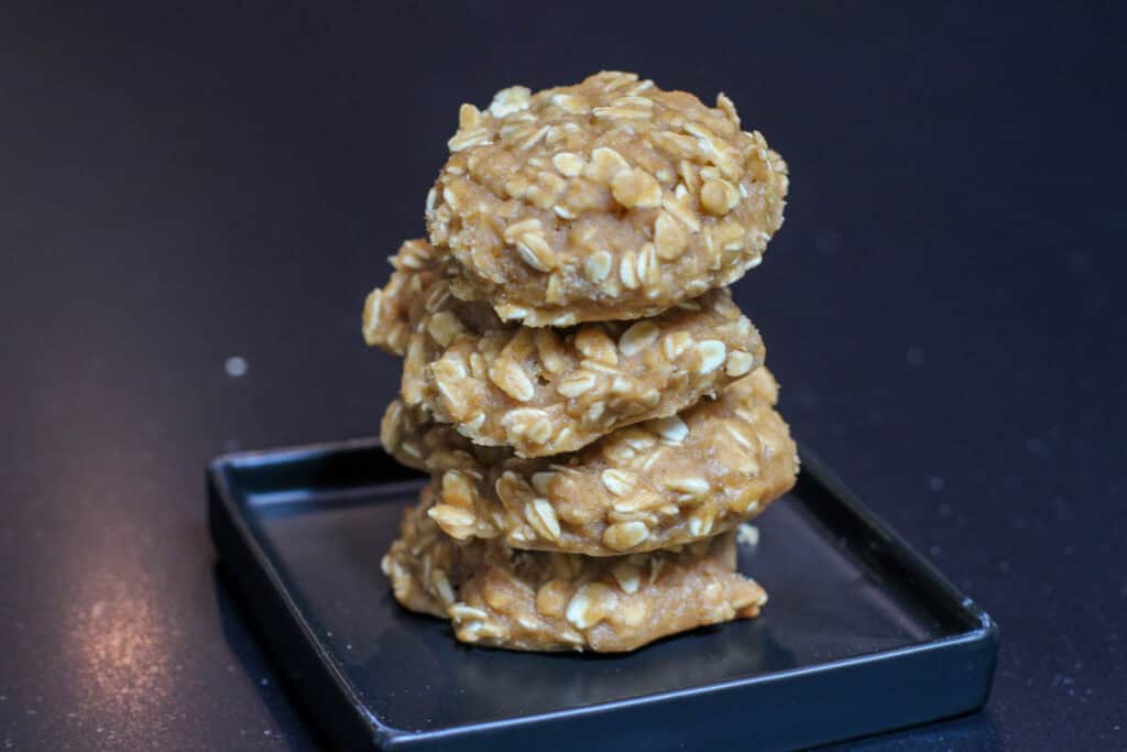 Stack of chewy high carb oatmeal cookies on a black plate, made with rolled oats and designed as homemade endurance fuel for cyclists and long training days.