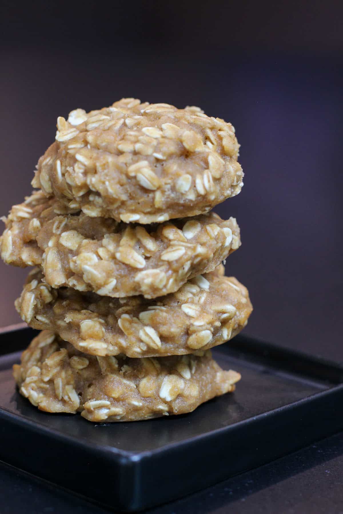 Stack of chewy high carb oatmeal cookies on a black plate, made with rolled oats and designed as homemade endurance fuel for cyclists and long training days.