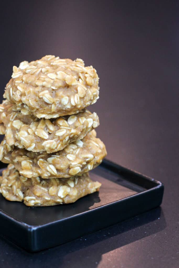 Stack of chewy high carb oatmeal cookies on a black plate, made with rolled oats and designed as homemade endurance fuel for cyclists and long training days.