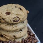 Stack of sea salt espresso chocolate chip cookies surrounded by roasted coffee beans, highlighting the espresso flavor in the cookies.