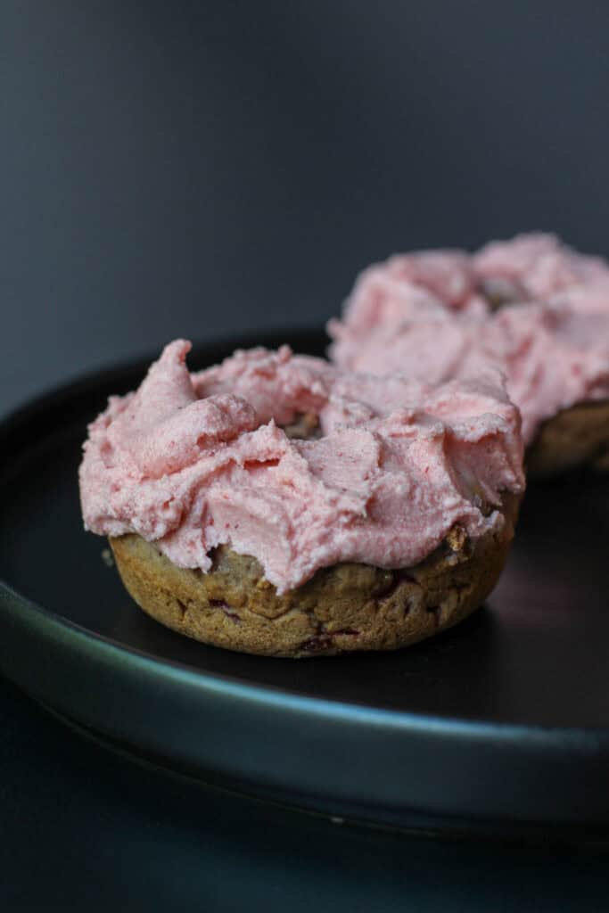 Close-up baked strawberry donut topped with fresh strawberry buttercream frosting.